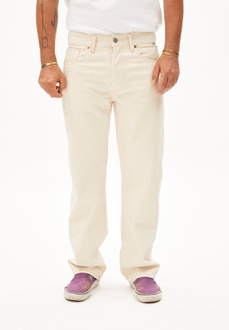 Licht beige denim jeans met een rechte pijp, voorzien van vijf zakken en koperen hardware-details. Draag met paarse instapschoenen.