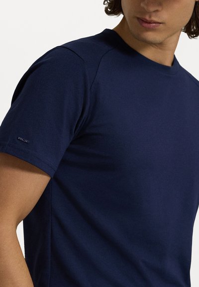 Μπλέ ναυτικού t-shirt κατασκευασμένο από μαλακό βαμβάκι. Διαθέτει στρογγυλή λαιμόκοψη και κοντά μανίκια, με ένα μικρό λογότυπο στο αριστερό μανίκι. Λείο ύφασμα.