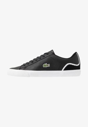Sneaker bassa in pelle nera con suola bianca, lacci neri, rifinitura bianca vicino al tallone e un logo di coccodrillo verde sul lato.