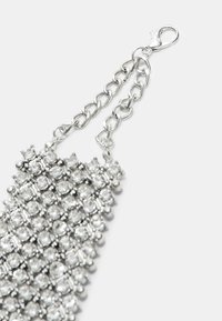Silberfarbener Armband mit mehreren klaren Rhinestones, die in einem Rautenmuster angeordnet sind, sowie einer Kette und einem Verschlussdetail.