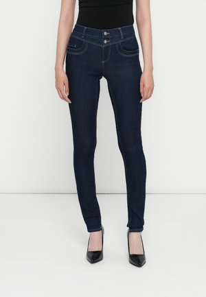 Jean skinny en denim bleu foncé à taille haute, avec deux poches avant, fermeture à deux boutons et détails de couture contrastants.