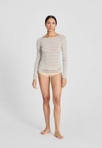 Long-sleeve striped top in neutral colors, with a rounded neckline and fitted shape. Soft fabric texture, paired with light-colored briefs.