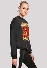 Schwarzer Sweatshirt mit Rundhalsausschnitt, ausgestattet mit einem bunten "Rolling Stones"-Grafik, Kordelzug am Saum und gerippten Bündchen.