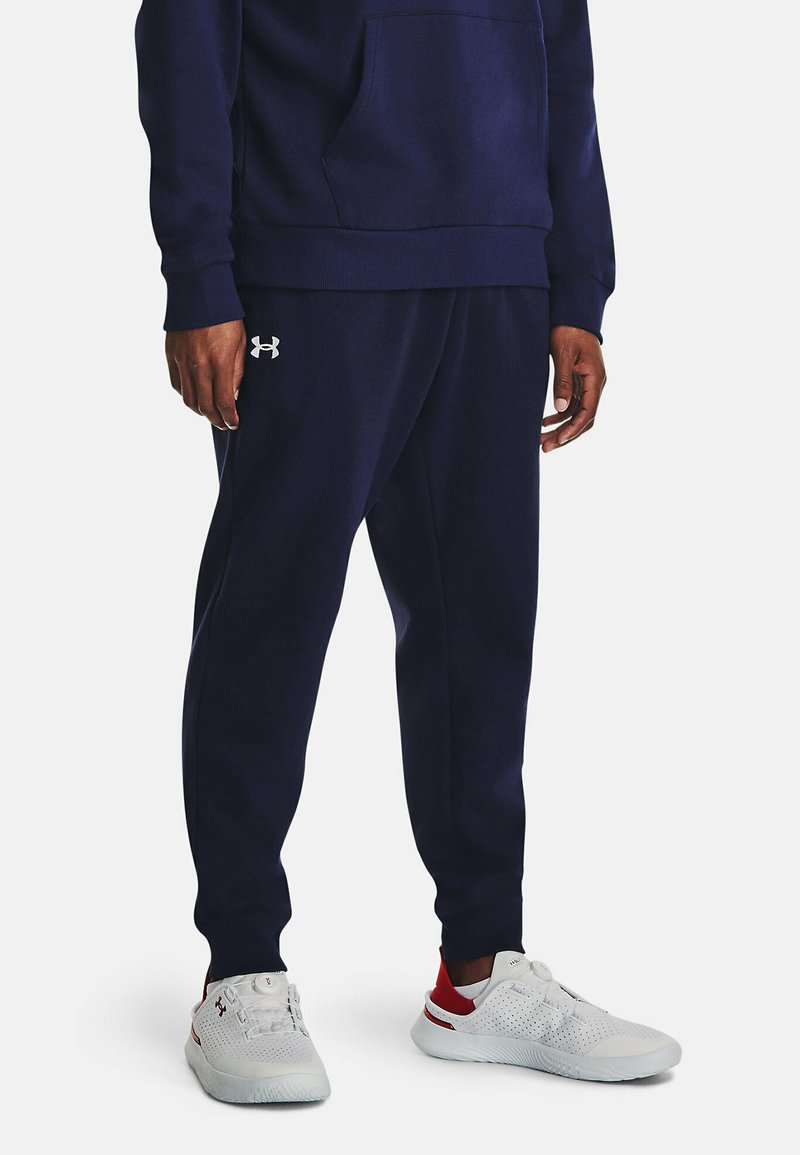 Sudadera azul marino con un bolsillo frontal y puños acanalados, combinada con pantalones jogger a juego. Presenta un logo blanco en el muslo izquierdo.