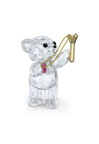 Klar kristallbjörnfigur som håller en slangbella, med svarta ögon, en rosa fluga och en skinande gyllene slangbella med en texturerad yta.