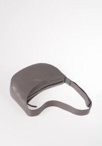 Borsa in pelle grigia con una forma rotonda unica, dotata di chiusura con zip e tracolla regolabile per un trasporto sicuro. Texture liscia.