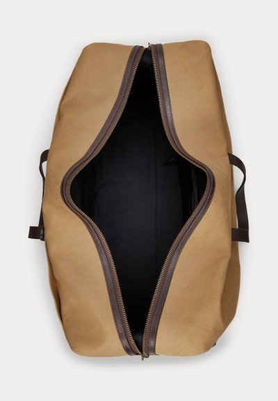 Large tan canvas duffel bag with dark brown leather trim and open zipper, showing empty black interior. Two side handles visible.