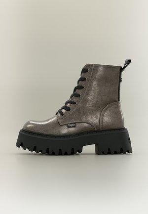 Bota de combate gris de cuero con cordones, suela gruesa negra con tacos y lengüeta en la parte trasera, mostrada sobre un fondo claro.