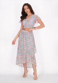 Floral zwei-teiliges Set mit einem kurz geschnittenen Oberteil und einem High-Low-Rock. Leichter Stoff in Pastellfarben mit einem Volantsaum.