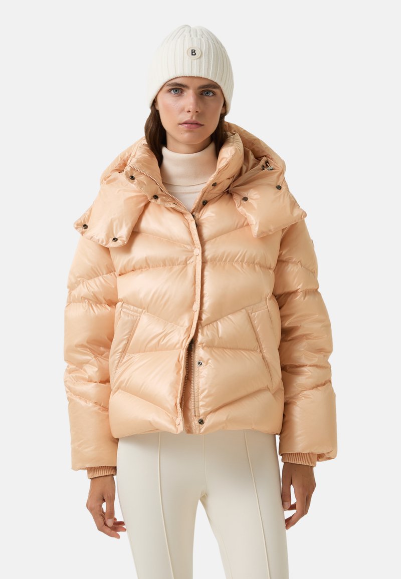 Kurtka puchowa w jasnym brzoskwiniowym kolorze z błyszczącym wykończeniem, wyposażona w odpinany kaptur, zatrzaski i kieszenie boczne. Żebrowane mankiety i ciepły design.
