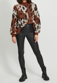 Knit animal print sweater in rust, black, and cream. Paired with high-waisted black leather leggings and black ankle boots.