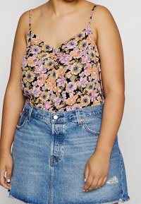 Svart blommig camisole med rosa, blå och gula blommor, med tunna spaghetti.rm. Kombineras med en jeanskjol.