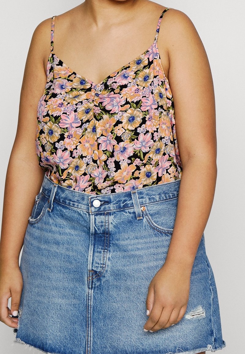 Svart blommig camisole med rosa, blå och gula blommor, med tunna spaghetti.rm. Kombineras med en jeanskjol.