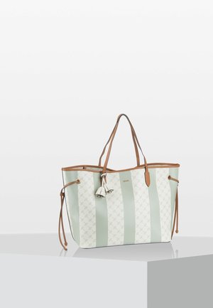 Grand sac fourre-tout avec des rayures verticales alternées vert clair et blanc, poignées en cuir marron, liens latéraux et breloques à pompons floraux.