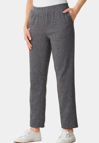 Pantalon à motif chevron gris avec une taille élastique, des poches latérales et des jambes droites, associé à des baskets blanches.