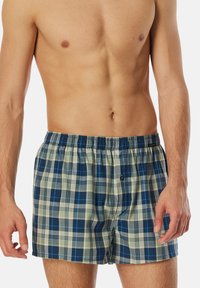 Boxeurs à carreaux pour hommes avec un motif à damier bleu et crème, taille élastique et un bouton unique à l'avant. Tissu en coton.