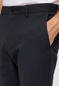 Dunkelblaue Hosen aus glattem Stoff mit schlanker Passform, ausgestattet mit einem Knopfverschluss, schrägen Taschen und dezenten Steppnähten.