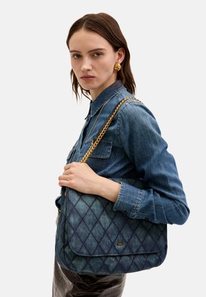 Gep quiltete Jeans-Schultertasche mit einer goldenen Kettenriemen, die eine glatte Textur und einen Klappenverschluss aufweist, vor einem neutralen Hintergrund präsentiert.