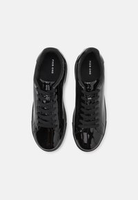 Schwarze Lackledersneaker mit runder Spitze, flachen Schnürsenkeln und kontrastierendem schwarzen Innenraum. Verfügt über strukturierte Akzente und minimalistische Markenkennzeichnung.