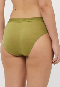 Zelené dámske nohavičky vyrobené z mäkkého, elastického materiálu. Majú pás s logom a bezšvový dizajn pre pohodlie a hladký strih.