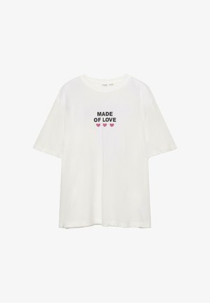 Valkoinen puuvillapaita lyhyillä hihoilla, jossa on mustalla tekstillä "MADE OF LOVE" ja sen alla kolme vaaleanpunaista sydäntä.