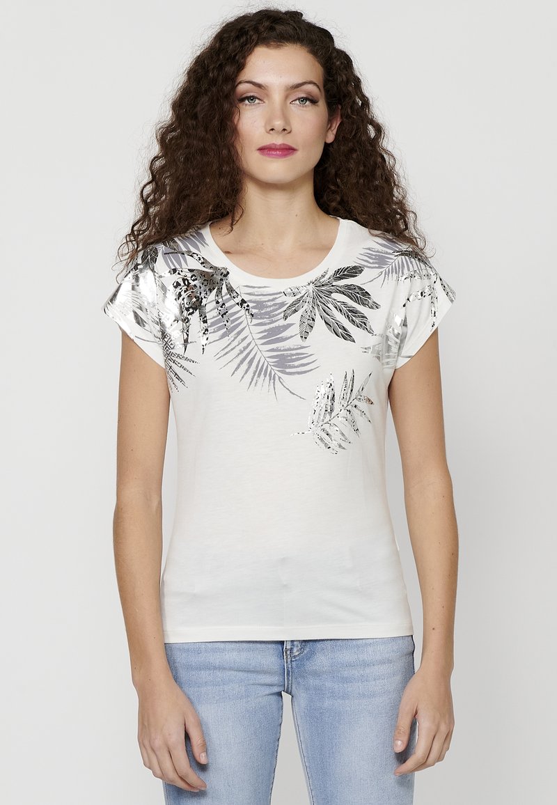 T-shirt blanc à manches courtes, ornée d'impressions en feuilles métalliques argentées et grises. Texture lisse, encolure ronde et design ajusté.