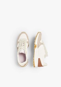 White and light beige sneakers with suede accents, textured rubber sole, and lace-up design. Features logo detail near the heel.