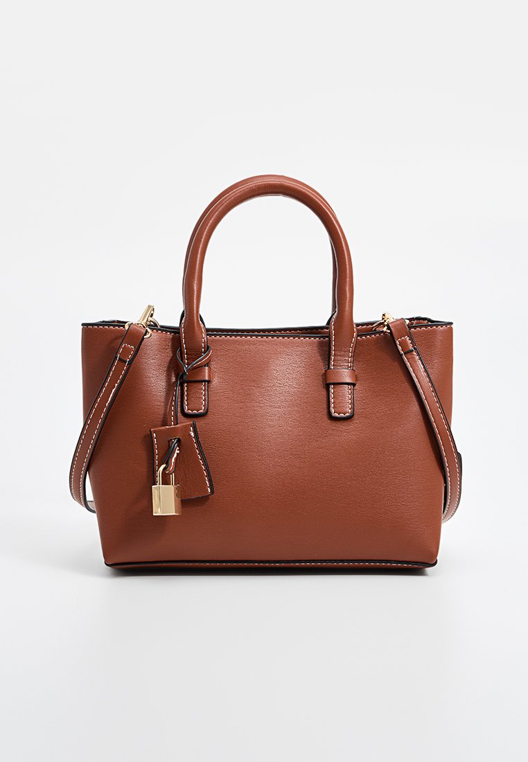 Sac à main en cuir marron avec deux poignées supérieures, accessoires en or et un charm en forme de cadenas amovible. Présente des coutures blanches contrastantes et une bandoulière détachable.