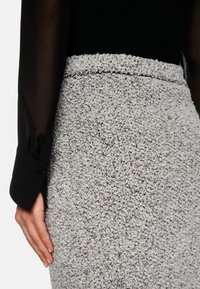 Gray textured skirt with a soft, fleecy appearance, paired with a black sheer long-sleeve shirt, featuring cuff detail.