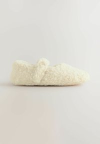 Vita fluffiga tofflor med ett strukturerat, mjukt material. Har en rund tå och en liten rosett som accent på ovansidan. Platt sula.