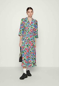 Vestido midi com estampado floral em azul, com vivos acentos em vermelho, verde e preto. Tecido leve, decote em V, mangas de três quartos e design em camadas.