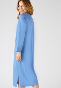 Abito blu a maniche lunghe realizzato in tessuto morbido, con uno spacco laterale e dettagli decorativi sui polsini. Design semplice e rilassato.