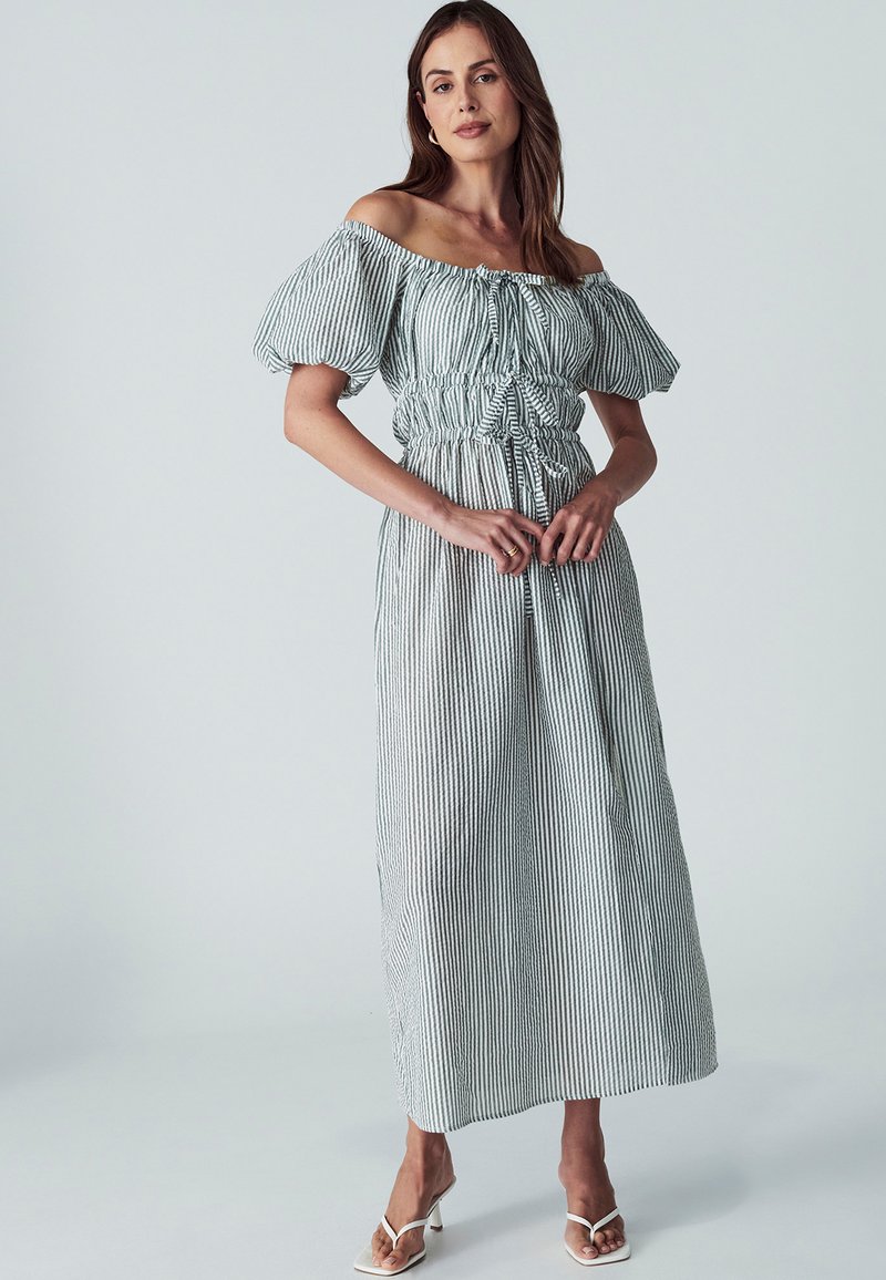 Gaišs, bezplecu maxi kleita zaļi un baltās svītrās, ar pūkainām piedurknēm, savelkamu vidukli un plūstošu, teksturētu audumu.