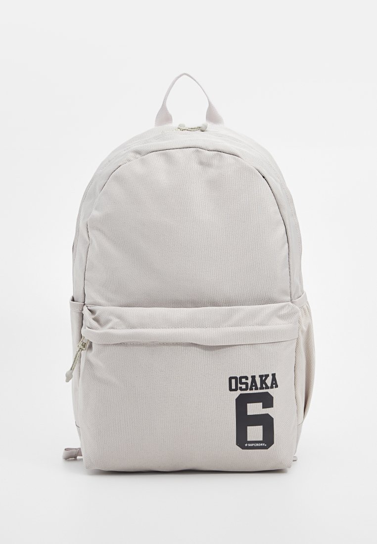 Lichtgrijze rugzak van gestructureerde stof, met een voorvak, een handvat aan de bovenkant en een afdruk van "OSAKA 6" op de onderste voorkant.