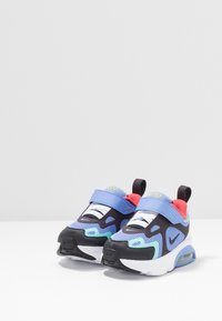 Flerfärgade sportskor med blått, svart och grönt mönster, meshpaneler, vadderad plös och justerbart spänne.