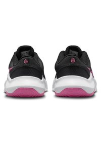 Baskets de sport noires avec une tige en mesh, une semelle intermédiaire blanche et une semelle extérieure rose. Présente un logo brodé en rose à l'arrière.