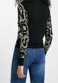 Cardigan noir avec des manches à motif rayé coloré. Caractéristiques : poignets et ourlet côtelés, coupe ajustée et texture lisse.