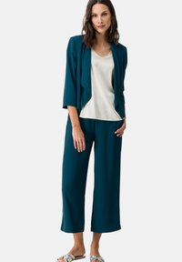 Teal three-piece outfit featuring a lightweight jacket, cream top, and wide-leg pants. Soft fabric with a relaxed fit and minimal detailing.