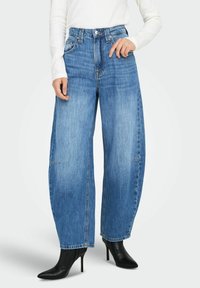 Široke traperice u svijetloplavoj boji, visokog struka, s glatkom teksturom. Uparene s crnim čizmama s potpeticom, koje pokazuju čist dizajn.