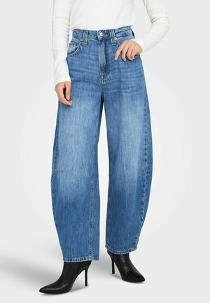 Heledad denim püksid helesinises toonis, kõrge vöökohaga, sileda tekstuuriga. Koos terava nina ja kontsaga mustade saapadega, mis tõstavad esile puhta disaini.