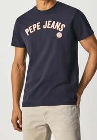 Marineblaue Baumwoll-T-Shirt mit kurzen Ärmeln, mit "PEPE JEANS" in korallenfarbenem Bogen-Text bedruckt. Schlichtes Design mit Rundhalsausschnitt und ohne sichtbare Muster.