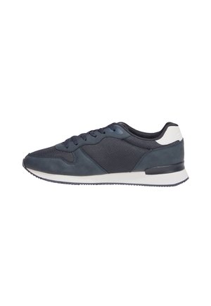 Chaussures de sport navy avec un mélange de cuir et de mesh, présentant un bout arrondi, un accent de talon blanc contrastant et une semelle plate en caoutchouc.