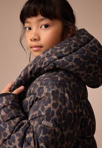 Kurtka puchowa z wzorzystym wzorem w ciemnych i jasnych brązach, z kapturem, pikowaną teksturą oraz logo na rękawie.