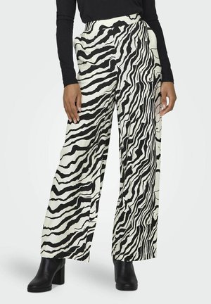 Spodnie o szerokich nogawkach w czarno-białym wzorze zebry. Wykonane z gładkiego materiału, z wysokim stanem i kieszeniami. Połączone z czarnymi botkami na obcasie.