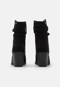 Czarne zamszowe botki do kostki z marszczonym wzorem, tylnymi suwakami i słupkowym obcasem. Podeszwa posiada teksturowany wzór antypoślizgowy.