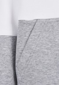 Grå sweatshirt med en myk bomullsblanding og en hvit toppdel. Har en sidelomme og et enkelt, rent design.
