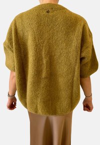 Maglione lavorato a maglia verde oliva con una superficie texturizzata, spalle cadute e orlo posteriore arrotondato. Include un piccolo logo vicino allo scollo.