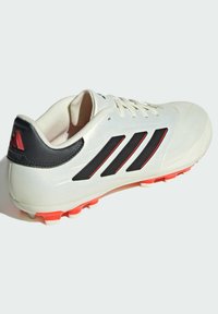 Scarpa da calcio bianca con dettagli neri e rossi. Presenta una tomaia in sintetico liscio, una punta leggermente testurizzata e tacchetti multi-color sulla suola.