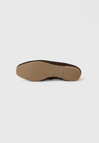 Καφέ σουέτ σόλα παπουτσιού με υφή, που διαθέτει λείο, ενισχυμένο τακούνι και ορθογώνιο διακοσμητικό στη πλευρά.