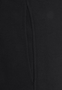 Close-up of black fabric showing a vertical seam with a subtle fold and fine knit texture.
